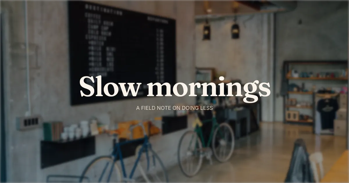 A softly blurred cafe interior, a chalkboard menu and two bicycles against a concrete wall, with Slow mornings set in a friendly serif over the kicker A Field Note On Doing Less - the texture-and-warm-palette move for lifestyle.