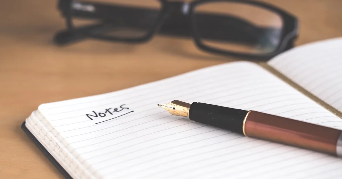 A flat-lay of glasses, an open notebook, and a fountain pen on a wooden desk - the kind of generic stock shot used on thousands of blogs.
